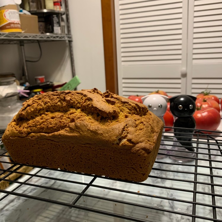 photo of pumpkin spice loaf cooling on a rack - the top is very craggily.